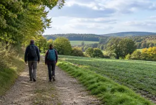 Deux randonneurs marchent sur un chemin de terre entre les champs et la lisière d’un bois près de Limours.